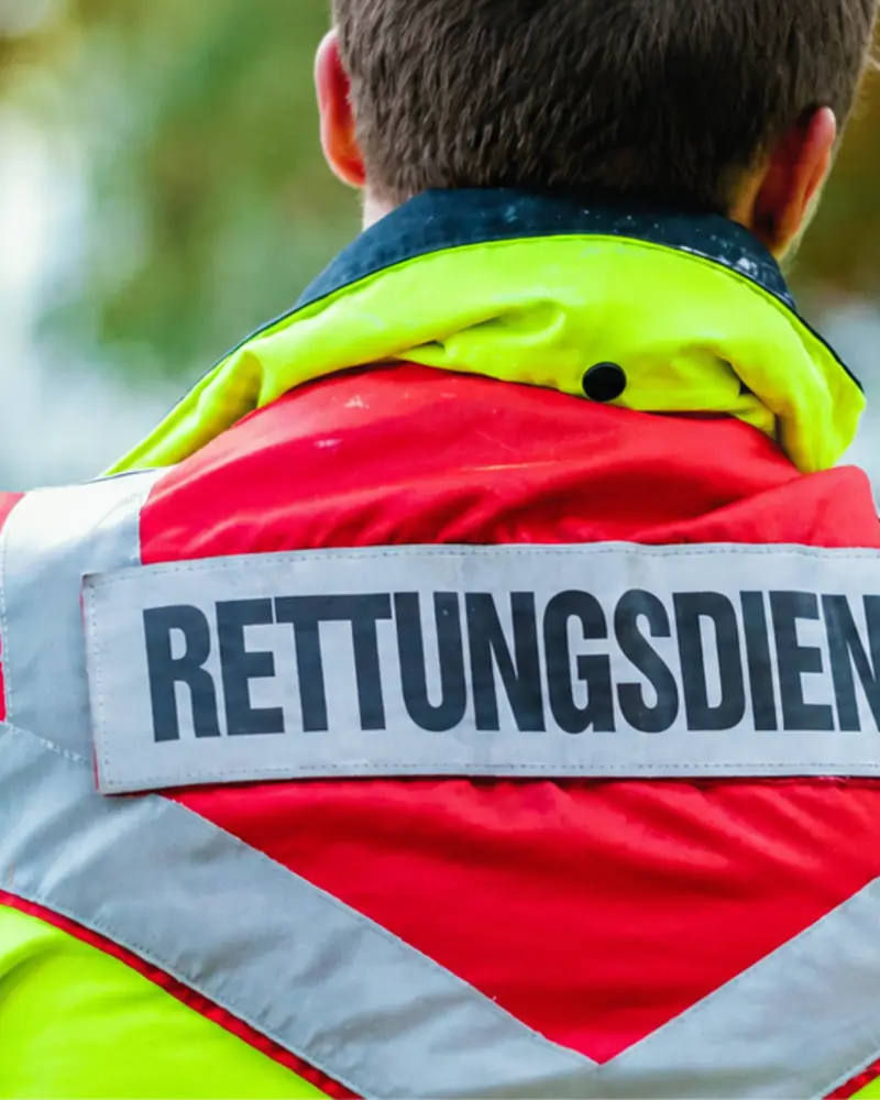 Rettungsdienstmitarbeiter von hinten mit der Aufschrift „Rettungsdienst“ auf der Einsatzjacke