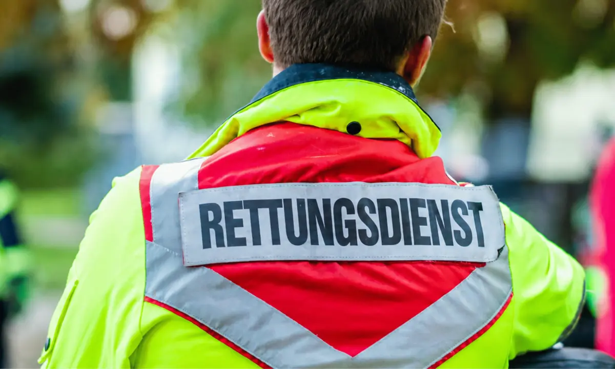Rettungsdienstmitarbeiter von hinten mit der Aufschrift „Rettungsdienst“ auf der Einsatzjacke